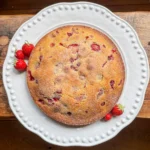 whole wild strawberry and polenta cake on a white plate