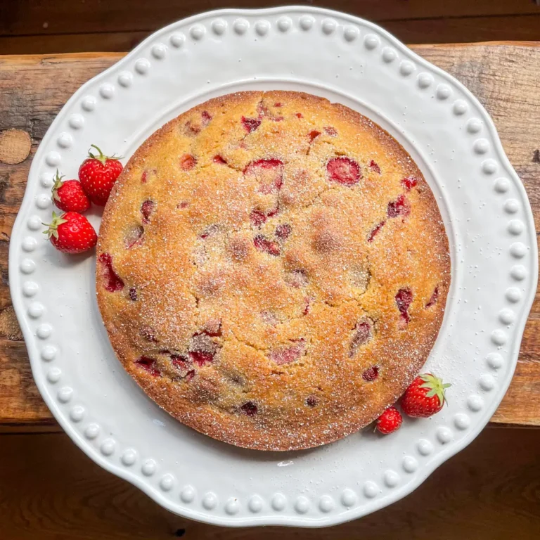 whole wild strawberry and polenta cake on a white plate